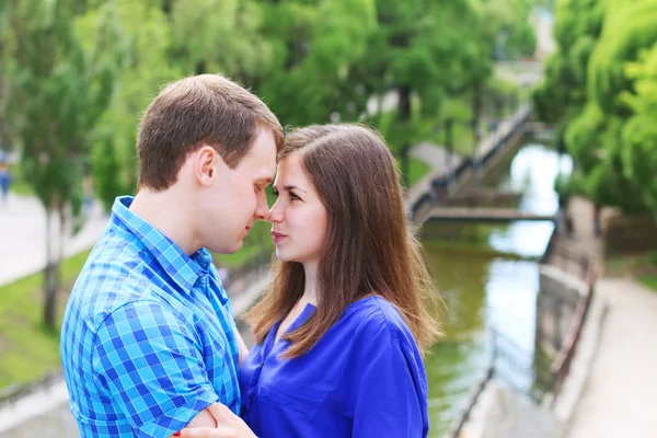 Young woman and man in blue touch noses in summer park with smal — Stock Photo, Image