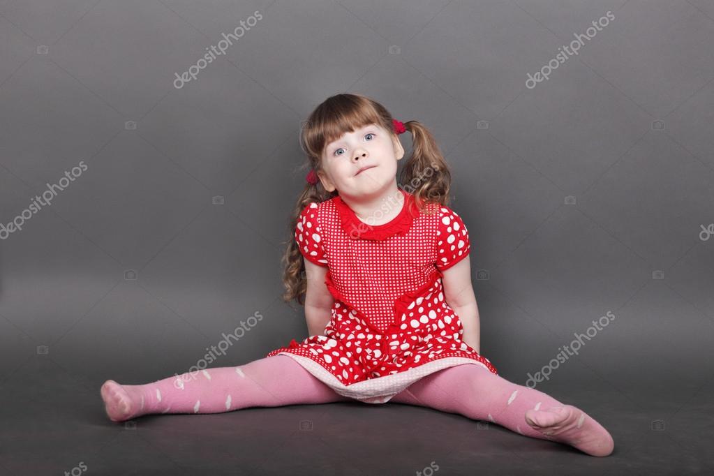 灰色のスタジオの床に座っている赤いドレスの面白い女の子 ストック写真 C Singulyarra1