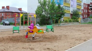 Küçük çocuk ve kız bulutlu bir günde oyun alanında döner kavşakta binmek