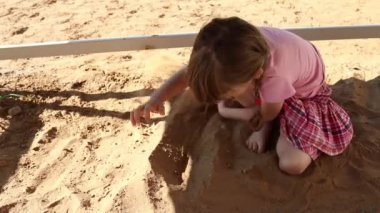 Mutlu küçük kız pembe kum ile sahada yaz çalış