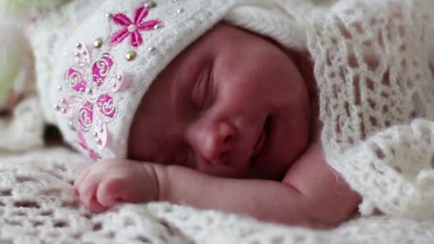 Little newborn baby in hat sleeps and grimaces on fluffy blanket — Stock Video