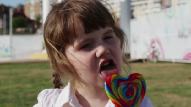 Küçük güzel kız yaz gününde açık lolipop yalıyor — Stok video