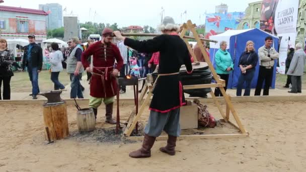 PERM, RUSSIA - JUN 12, 2014: Blacksmiths in period costumes work with bellows at International Festival Svarog Crucible — Stock Video