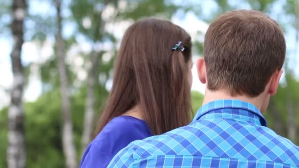 Feliz mujer y hombre joven sentarse en el banco y la mujer mira a la cámara — Vídeo de stock