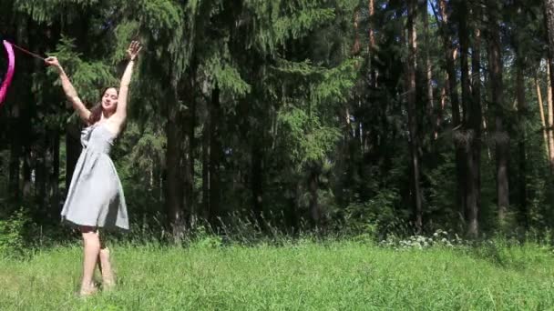 Jonge vrouw in jurk dansen met lint in zomer bos — Stockvideo