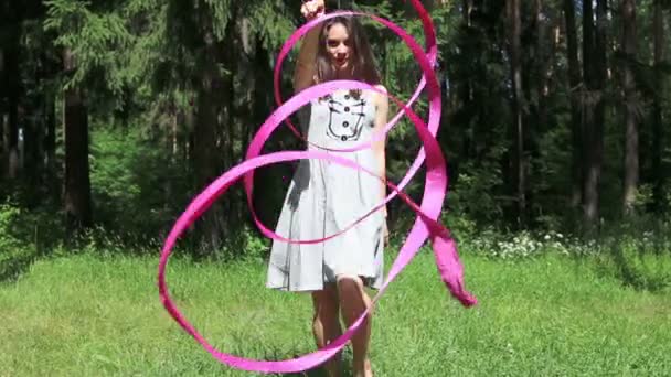 Pretty girl in dress goes back to forest and twists ribbon — Stock Video