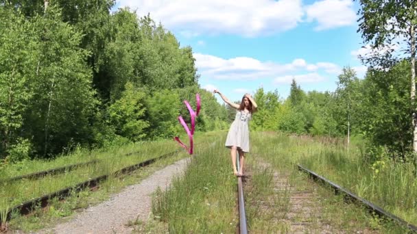 Schöne glückliche Mädchen mit Schleife geht auf alte Schiene an Sommertag — Stockvideo