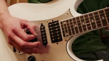 Eller genç adamın evde arabulucu ile beyaz gitar çalmak