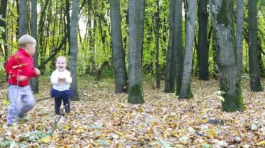 Küçük erkek ve kız koşmak ve sonbahar parkta eğlenin