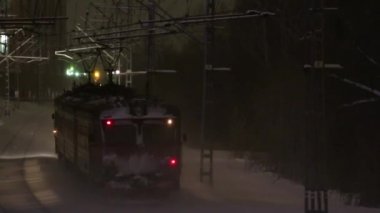 Küçük yolcu treni kar yağışı sırasında kış gecesi köprü altında demiryolu gider