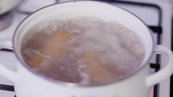 Вода и колбасы кипят в белом горшке на газовой плите на кухне — стоковое видео