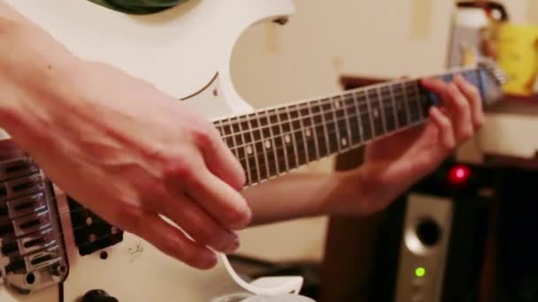 Händerna på ung man spelar modern vit gitarr hemma — Stockvideo