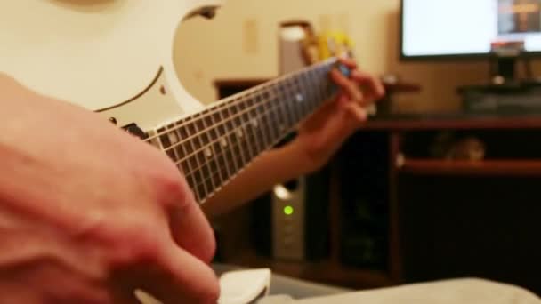 Руки людини, що грає на білій гітарі з посередником вдома — стокове відео