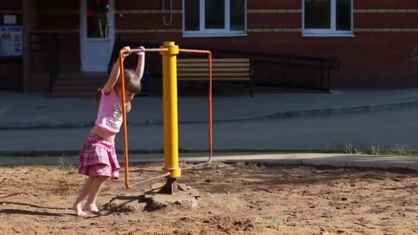 Liten söt flicka i rosa virvlar på snurra på lekplats — Stockvideo