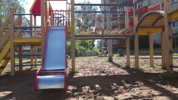 Kleiner Junge in Brille klettert bei sonnigem Wetter auf Spielplatz — Stockvideo