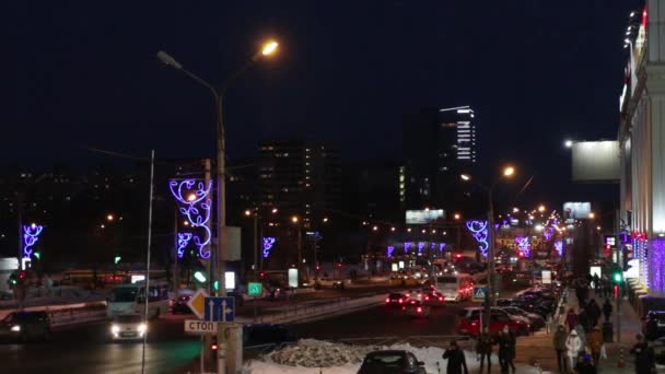 Машины и люди, выходящие на улицу в зимнюю ночь в городе — стоковое видео