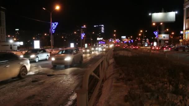 Cars going on street road with illumination at dark winter night in city. Variable depth of field — Stock Video