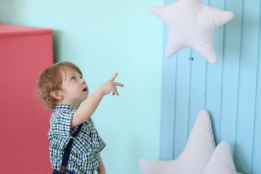 Küçük yakışıklı kıvırcık çocuk görünüyor ve yumuşak asılı star adlı Puan 