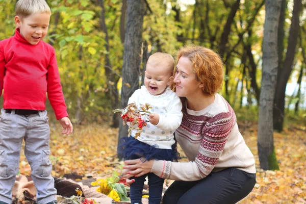 Young mother with two happy children with flowers — Stock Photo, Image