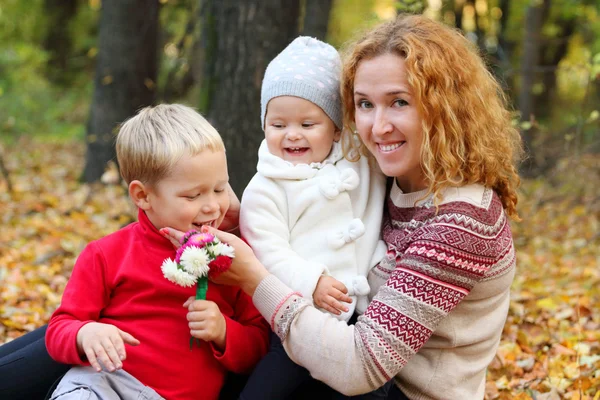 年轻的母亲和两个快乐的孩子们用鲜花 — 图库照片