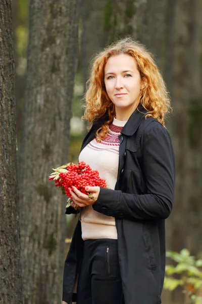 Mooie vrouw met een rode rowanberry glimlach — Stockfoto