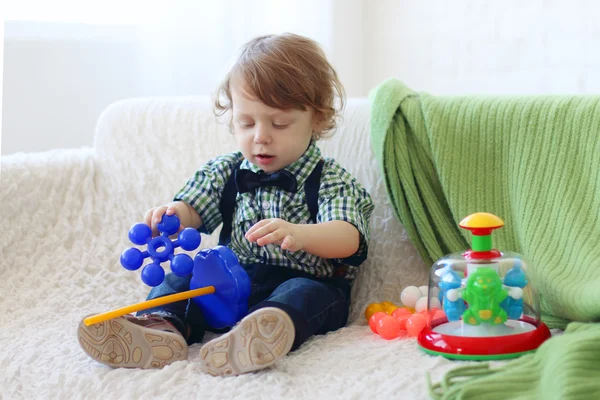 Knappe gelukkig jongetje zit op zachte sofa en speelt met speelgoed — Stockfoto