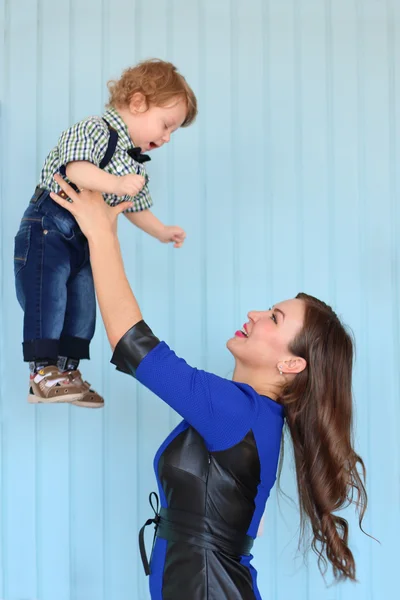 Krásná žena v modrých šatech hodí do malého syna — Stock fotografie