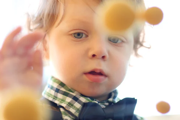 Porträt eines kleinen hübschen Jungen mit lockigem Haar, das Gelb berührt — Stockfoto