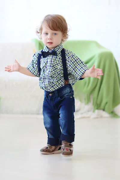 Kleiner hübscher lockiger Junge steht mit ausgestreckten Armen — Stockfoto