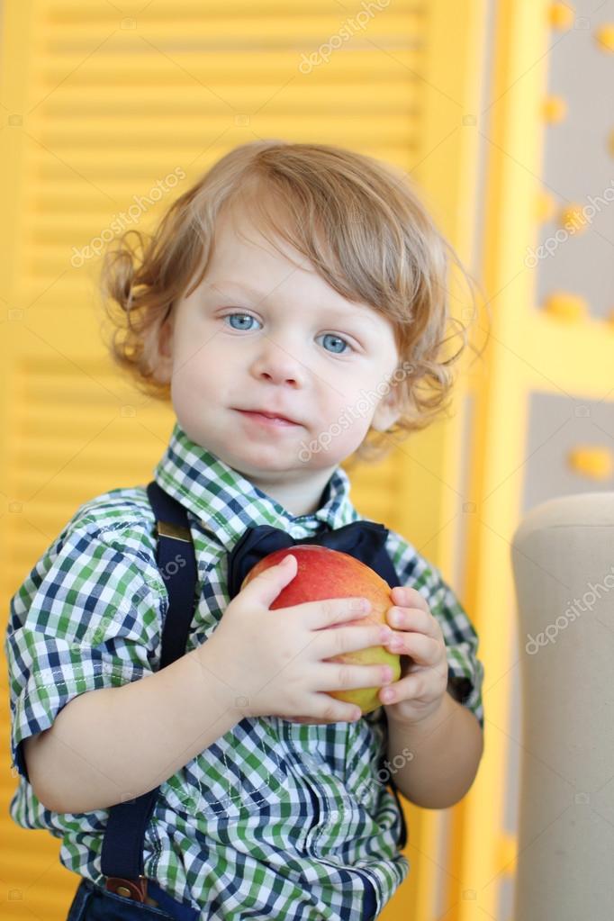 Little Cute Boy With Curly Hair Holds Apple Stock Photo