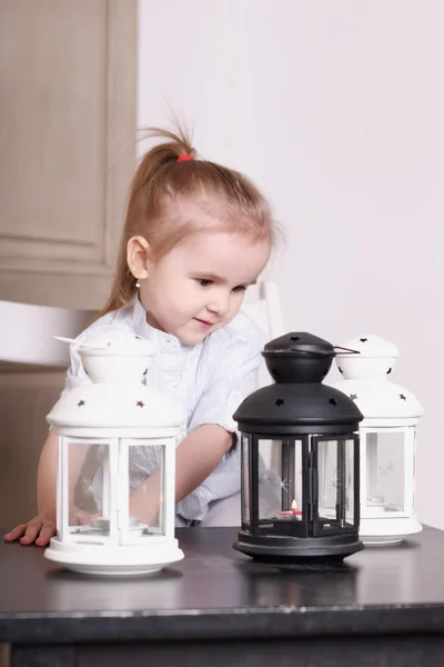 Cute little blond girl playing with three luminaires with candle — Stock Photo, Image