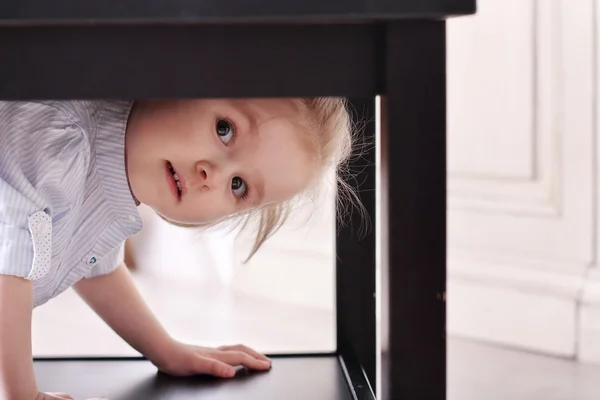 Cute little blond girl in striped shirt climbed in recess table — Stock Photo, Image