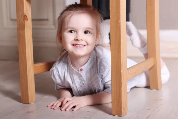 Piccola ragazza bionda carina in camicia a righe sta sorridendo sul pavimento unde — Foto Stock