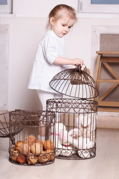 Little cute blond girl in striped shirt stands and playing cages — Stock Photo, Image