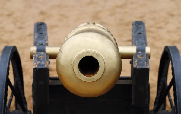 Closeup de focinho de canhão de metal velho com roda na areia ao ar livre — Fotografia de Stock