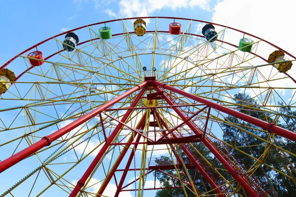 Colorful Ferris wheel and tops of trees and blue sky at summer — Stock Photo, Image