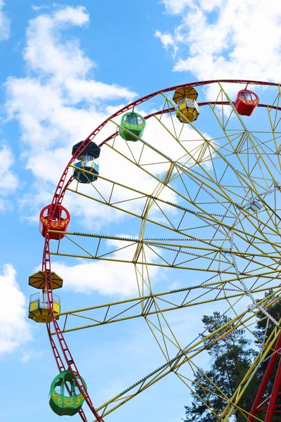 Half of colorful Ferris wheel and tops of trees and blue sky — Stock Photo, Image