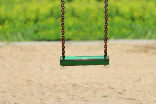 Zielony woioden huśtawka na łańcuch na plac zabaw w letni dzień — Zdjęcie stockowe