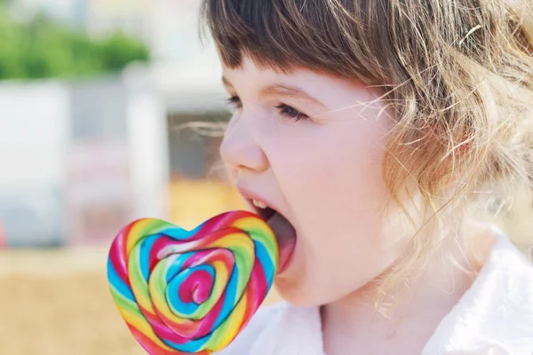 Bonne petite fille lèche la sucette lumineuse en plein air à l'été — Photo