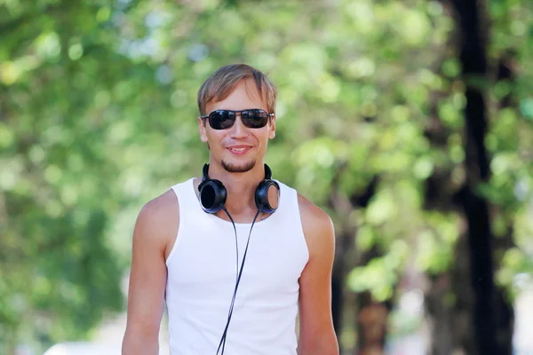 Lächelnder Mann mit Sonnenbrille und Kopfhörer in der Gasse — Stockfoto