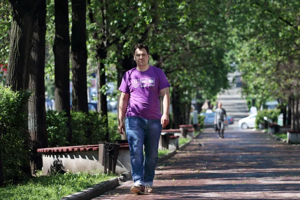 Чоловік в джинсах ходить в парку з зеленими деревами — стокове фото
