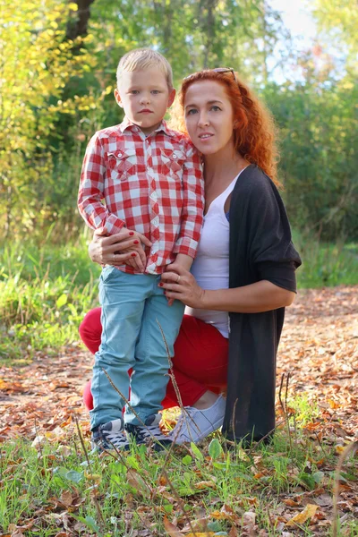 Young mother and handsome little son in autumn park at sunny day — Stock Photo, Image