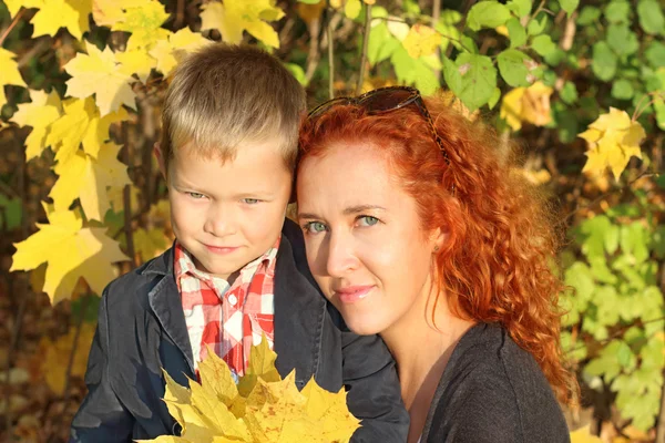 Mutter und kleiner Sohn mit gelben Ahornen im Herbstpark — Stockfoto