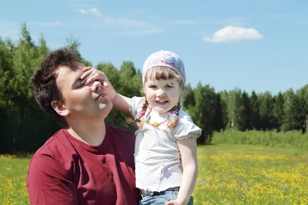 Junger Vater hält glückliche kleine Tochter nahe grünem Wald bei Su — Stockfoto