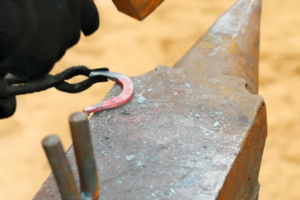 Detailní záběr na ruku kovářem kladiva horké podkovy zpracování — Stock fotografie