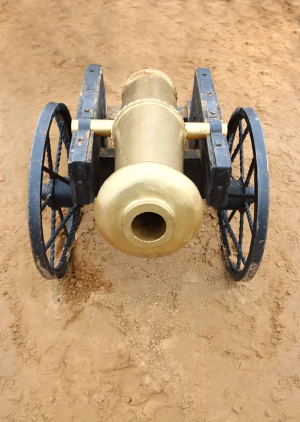 Vieux canon métallique jaune avec roues noires sur sable extérieur — Photo