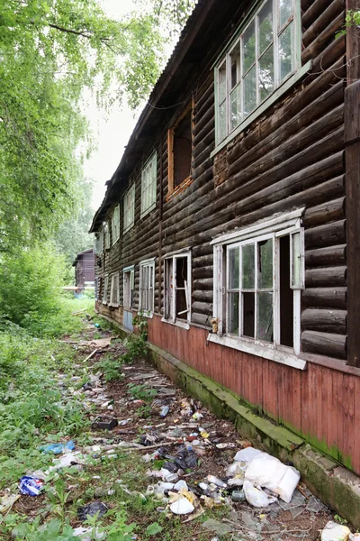 Velho edifício abandonado de dois andares de madeira com lixo no verão — Fotografia de Stock