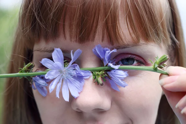 Close up portrait of beautiful woman hiding eye with wildflower — Stock Photo, Image