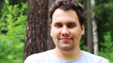 Yakışıklı adam gülümsüyor ve yaz Park teşkil etmektedir. Görünümü kapatın