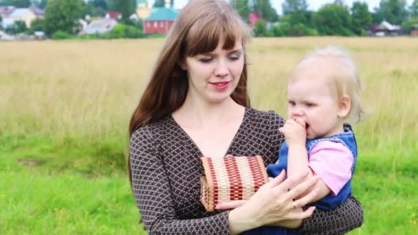 幸福的母亲抱着小女儿在绿色草地上在夏季的一天 — 图库视频影像